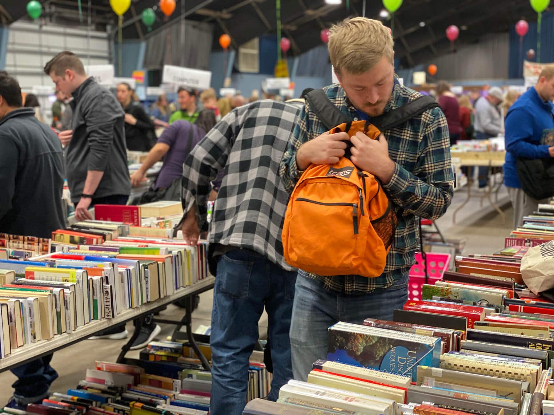 man looking for new books while carrying a backpack