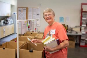 adult senior female smiling as she sorts books