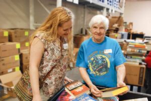two volunteers at booksale smiling