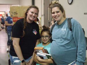 two young adults and a young girl smiling at booksale