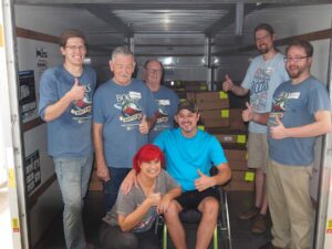 group smiling and helping to unload box truck